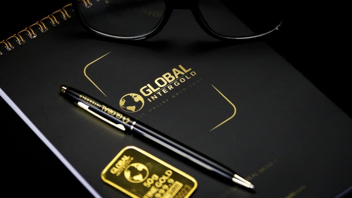 An elegant setup with a notebook, pen, and gold bar, embodying luxury and style.