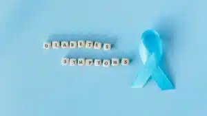 Conceptual image emphasizing diabetes symptoms with a blue awareness ribbon and letter dice.