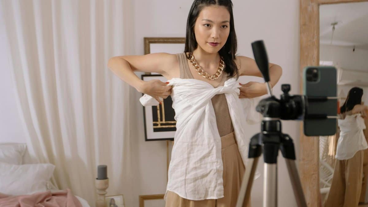 Fashion vlogger demonstrates styling tips while filming at home, enhancing personal fashion content.