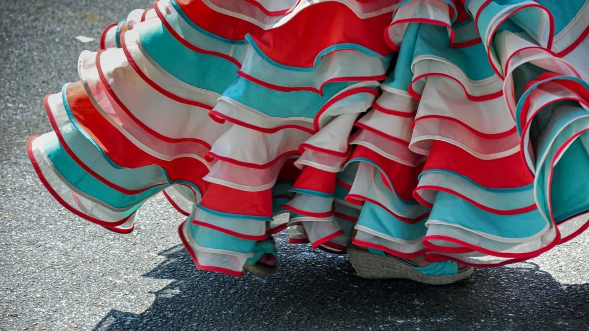 A vibrant flamenco skirt in red, teal, and white, captures traditional dance motion.