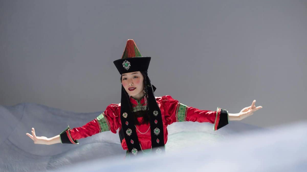 Asian woman in Mongolian traditional attire performing dance.