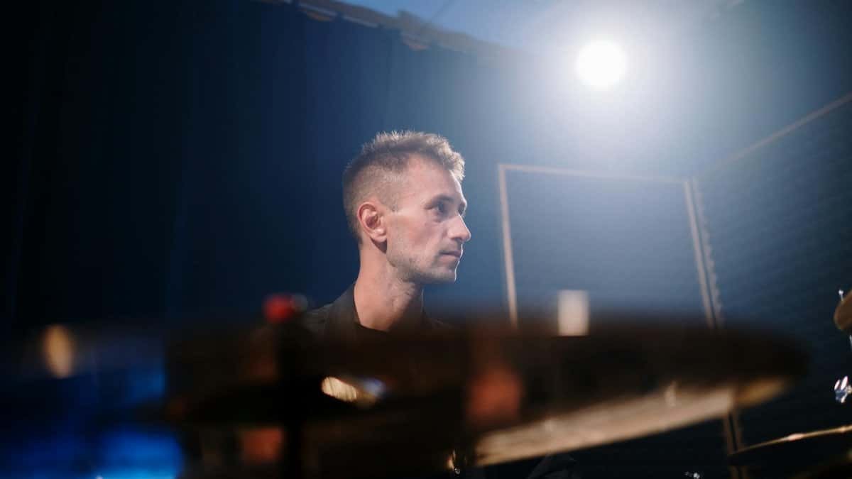 A portrait of a drummer in a studio setting with spotlight lighting, capturing a creative atmosphere.
