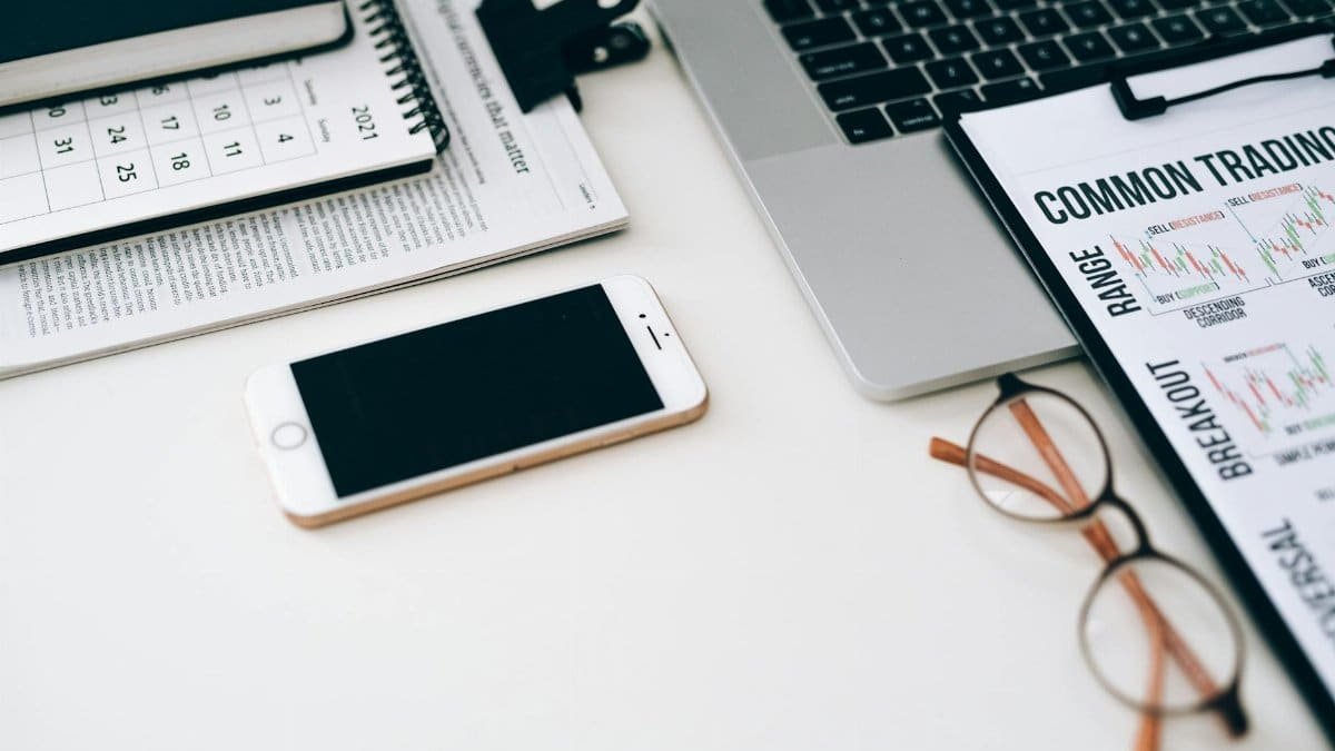 A well-organized office desk setup with finance documents, digital devices, and glasses.
