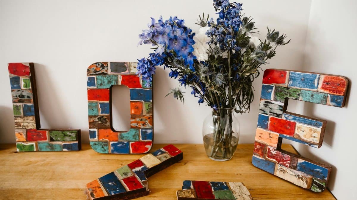 Colorful wooden love letters and vibrant floral bouquet in a rustic setting.