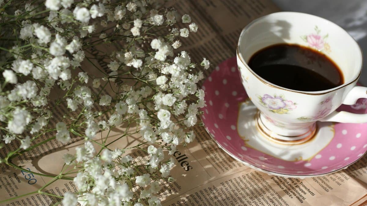 Charming floral coffee arrangement with Baby's Breath flowers on a newspaper backdrop.