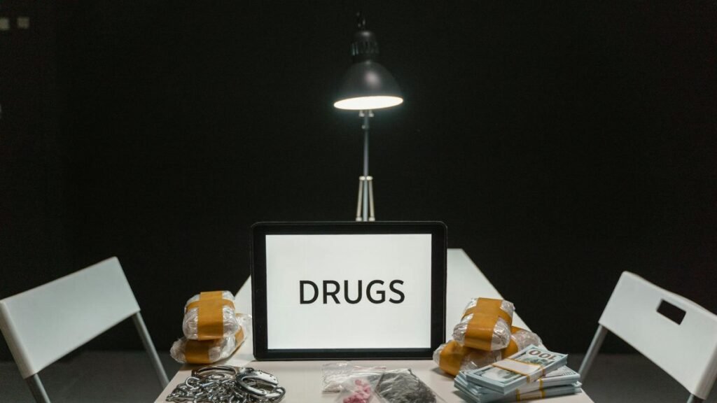 A dimly lit room with a sign displaying 'DRUGS' surrounded by money and illegal substances.