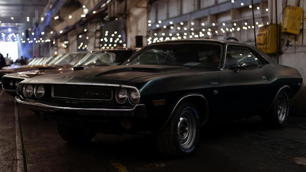 Vintage black Dodge Challenger parked in an industrial garage setting, evoking nostalgia and classic car elegance.