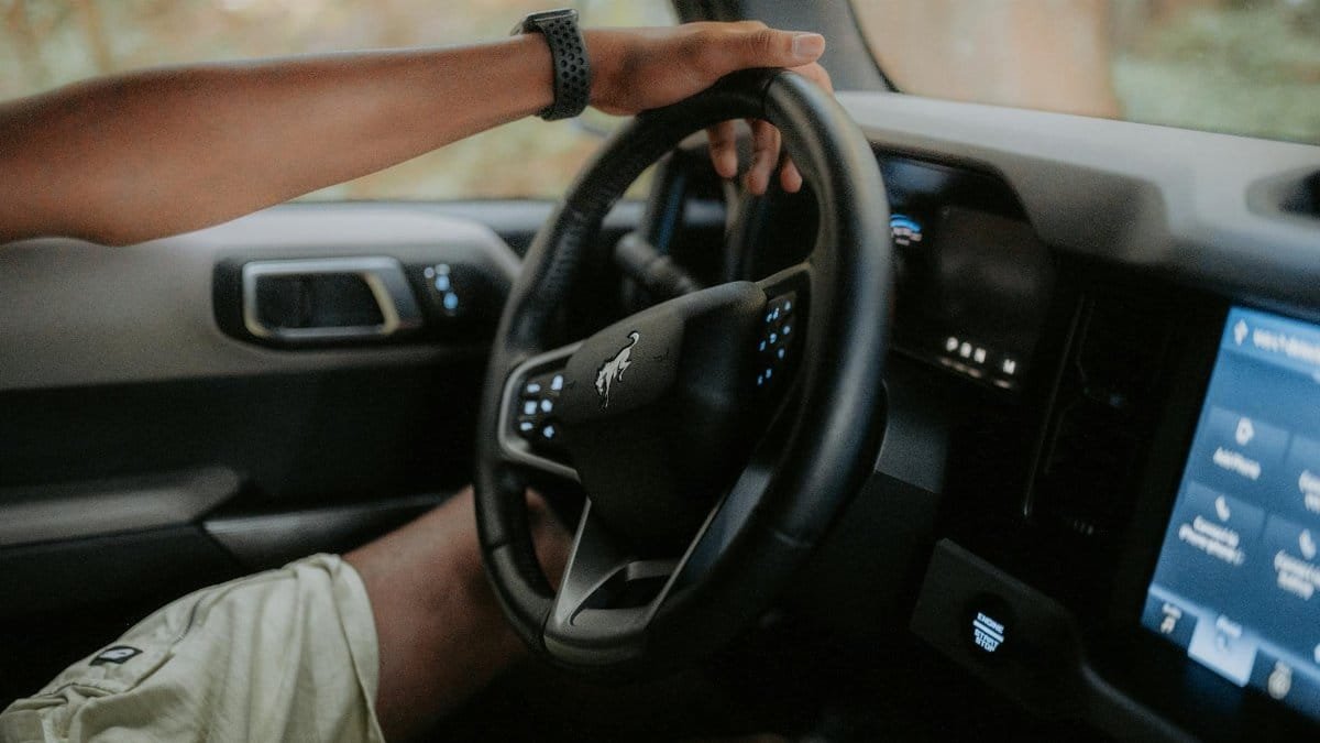 A person driving a modern car, focusing on hands and steering wheel.