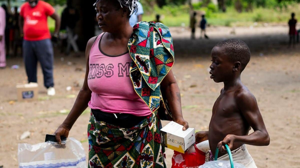 A woman and child carrying relief supplies outdoors, showcasing resilience and community support.