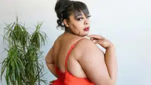 Body positive image of a plus size woman embracing self love in a red swimsuit.