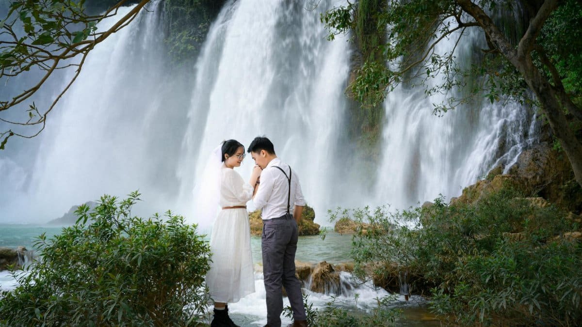 A couple shares a tender moment by the scenic Ban Gioc Waterfall in Cao Bang, Vietnam.
