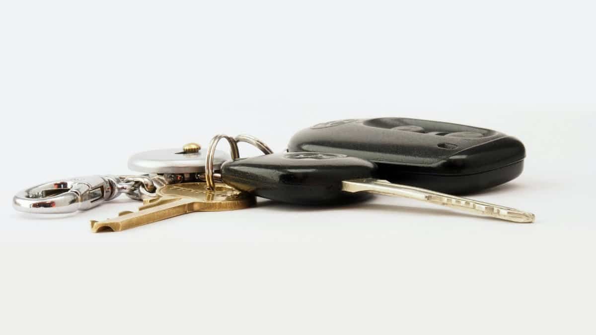 Detailed image of car keys on a white surface, including a key fob and keychain.