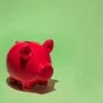 Red piggy bank on a green background symbolizing savings and financial planning.