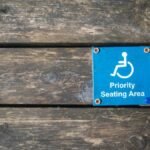 Close-up of a priority seating area sign with wheelchair symbol on a wooden surface.