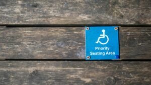 Close-up of a priority seating area sign with wheelchair symbol on a wooden surface.