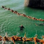 People participating in a water rescue training exercise, linked by life vests.