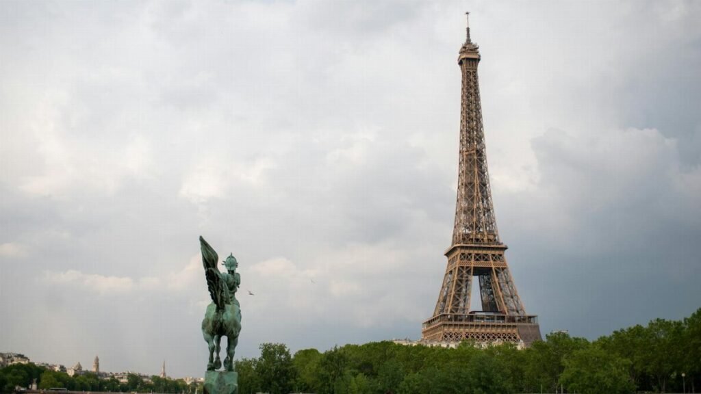 Iconic view of the Eiffel Tower alongside the equestrian statue La France Renaissante in Paris.
