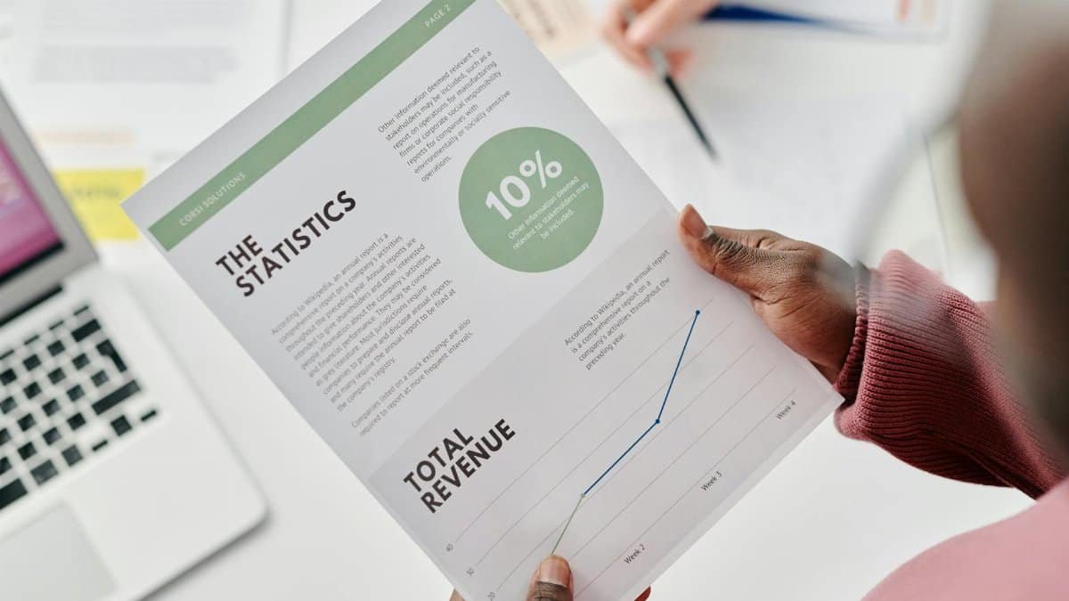 Hands holding a statistical report during a business meeting. Includes revenue graphs and analysis.