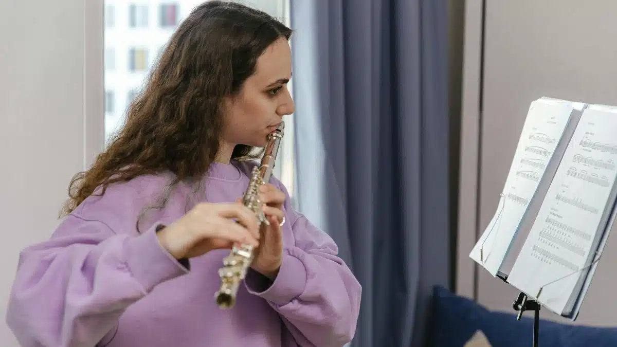 Side view of a woman playing the flute, reading sheet music, indoors.