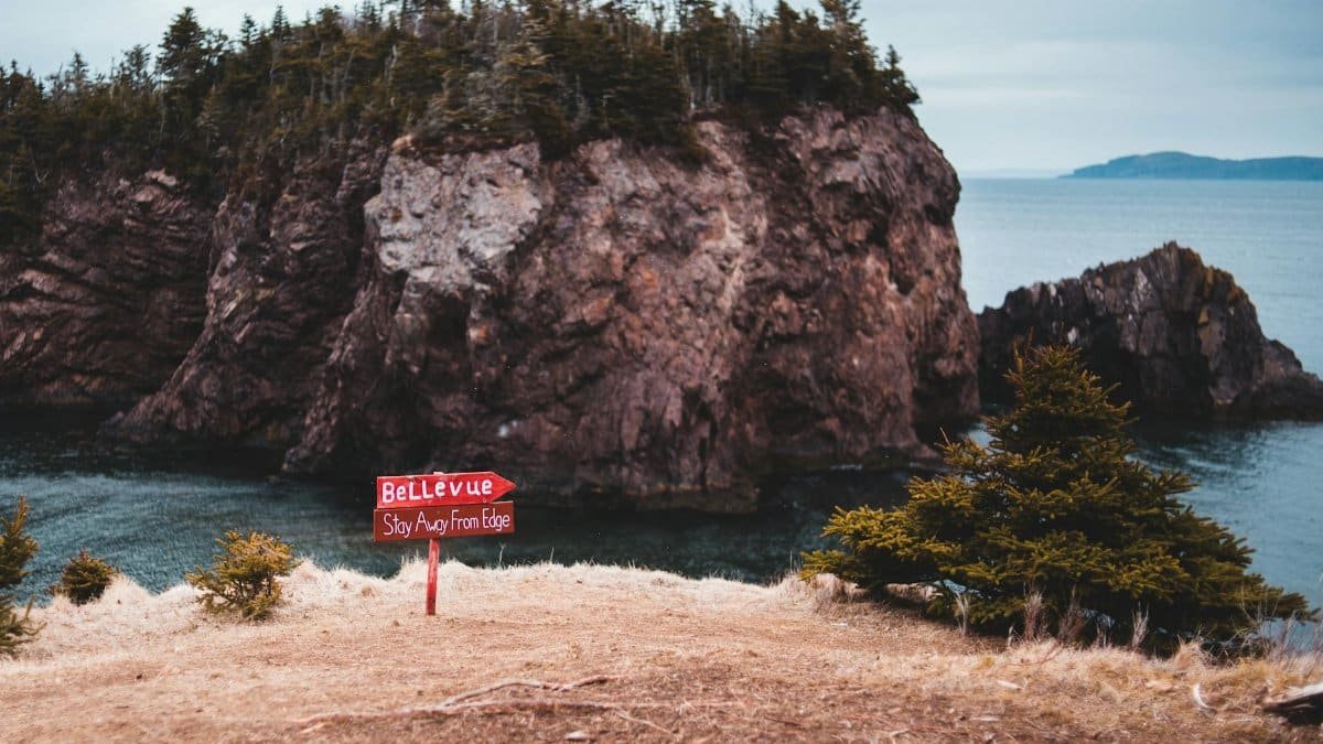 Serene landscape at Bellevue with a warning sign near the cliff edge overlooking the ocean.