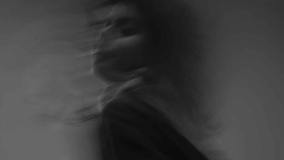 Artistic black and white photograph showcasing a woman's blurred motion in a studio setting.