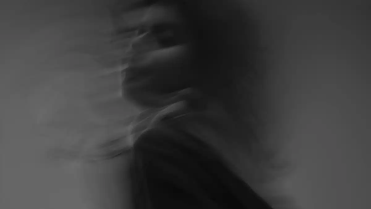 Artistic black and white photograph showcasing a woman's blurred motion in a studio setting.