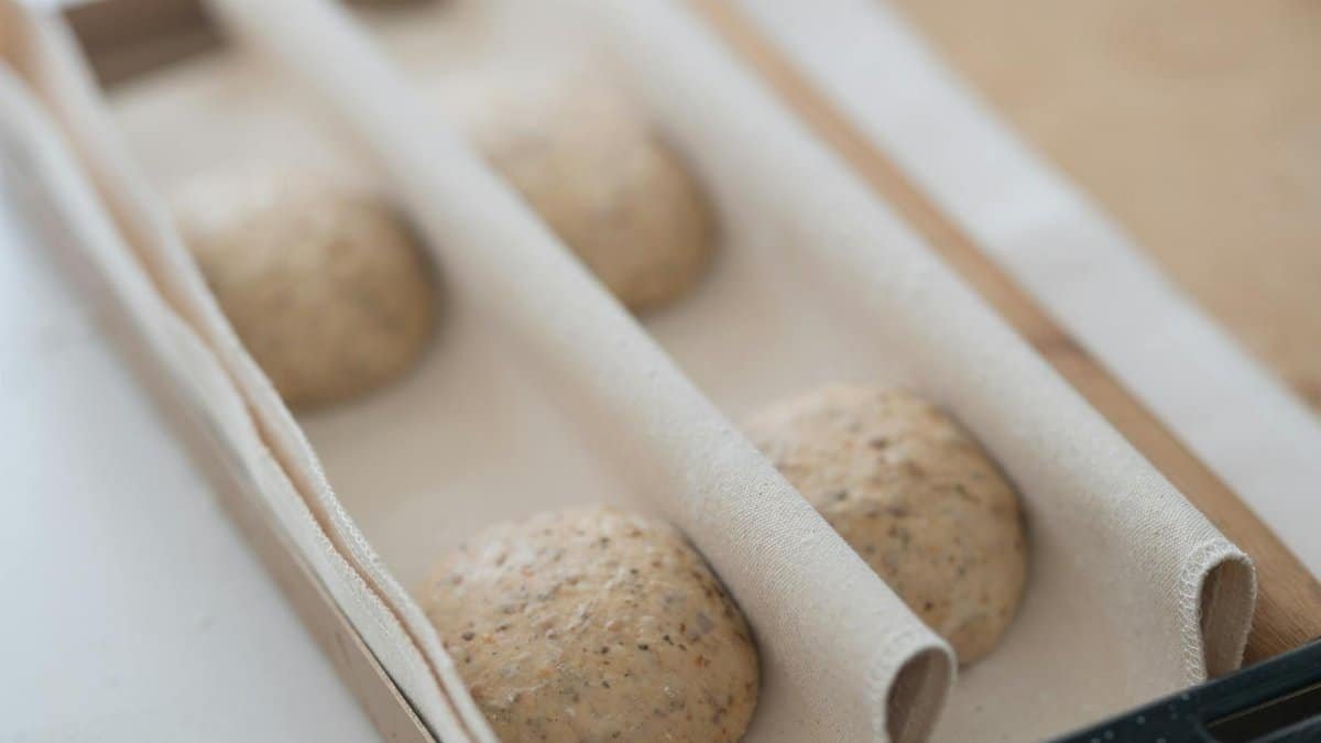 Close-up of artisanal sourdough bread dough proofing in a wooden box, ready for baking.
