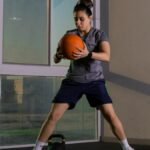 Focused woman working out indoors using a medicine ball for fitness training.