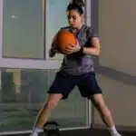 Focused woman working out indoors using a medicine ball for fitness training.