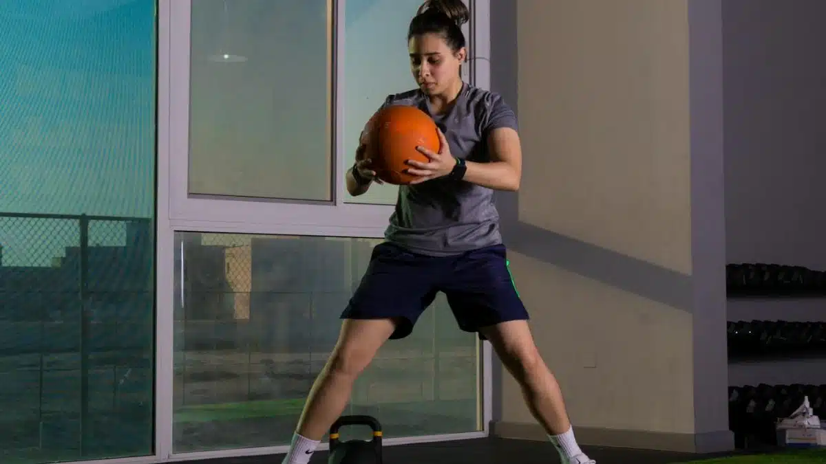 Focused woman working out indoors using a medicine ball for fitness training.