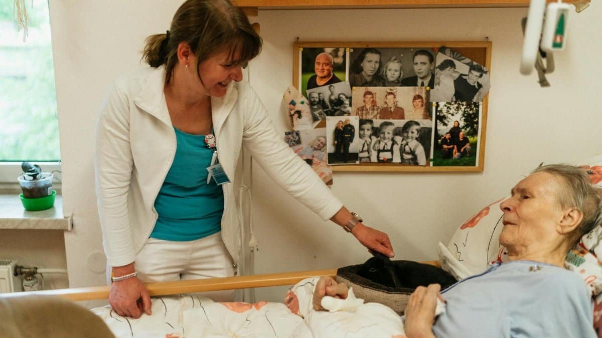 Nurse provides care for an elderly patient in a hospital room, showcasing empathy and professionalism.