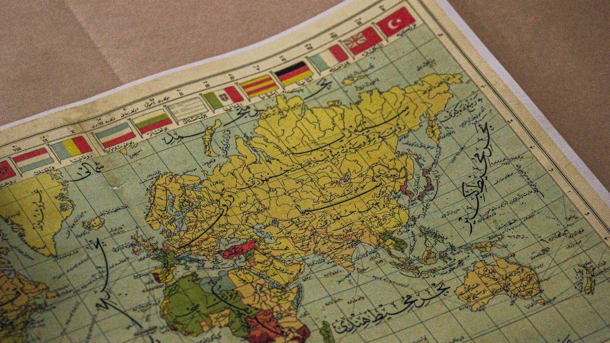 Antique world map showing continents, Arabic script, and various national flags.