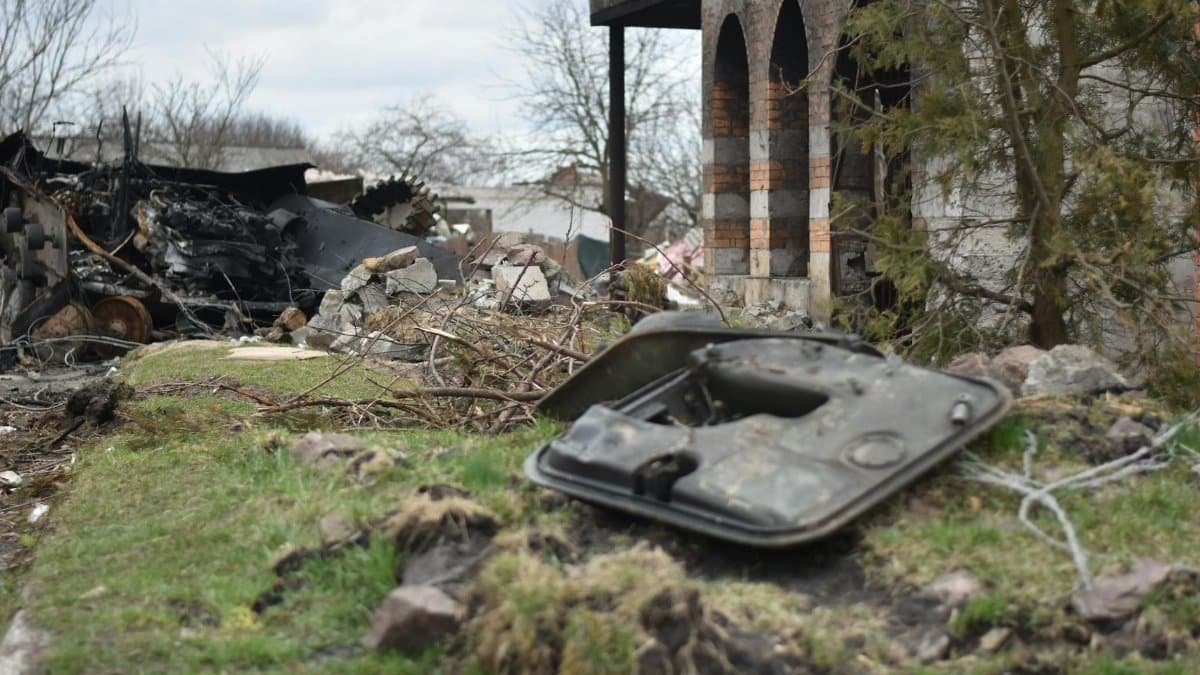 A desolate scene of ruins with rubble, debris, and a charred vehicle part in focus.