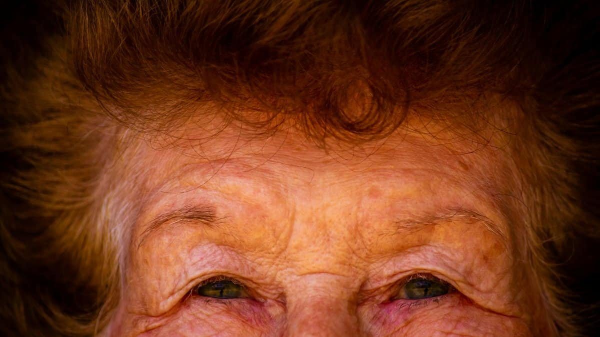 Detailed close-up shot of an elderly woman's wrinkled eyes and hair, emphasizing age and experience.