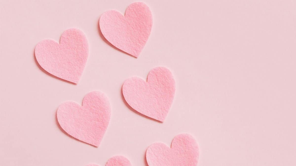 Six pink felt heart decorations arranged on a pastel pink background, perfect for romantic themes.