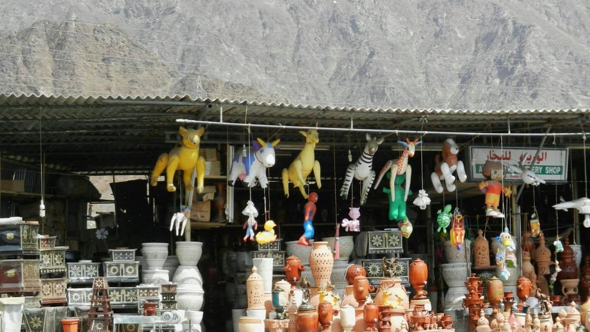 Colorful pottery and inflatable toys at an outdoor market against a mountain backdrop.