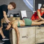 Athlete receives cupping therapy for muscle recovery in a gym setting with two therapists.