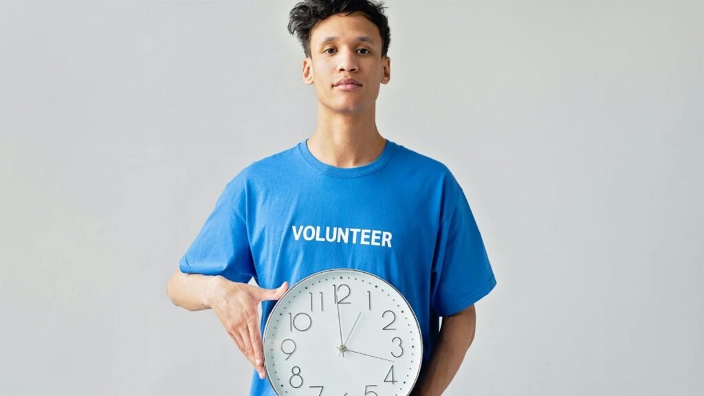 Young male volunteer in blue shirt holding a clock, symbolizing time management.
