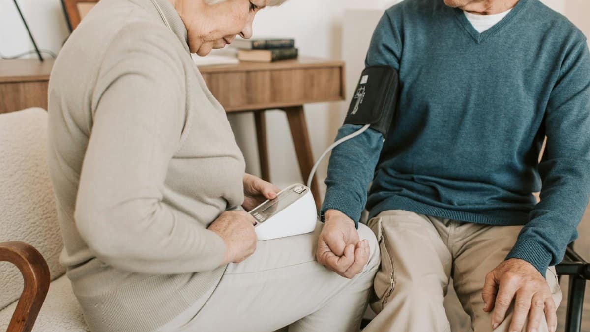 Senior couple at home measuring blood pressure for health check.