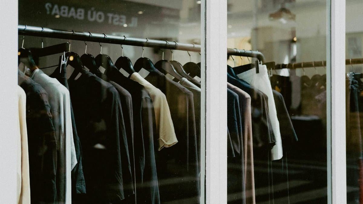 Close-up of clothing on hangers inside a fashion store window.