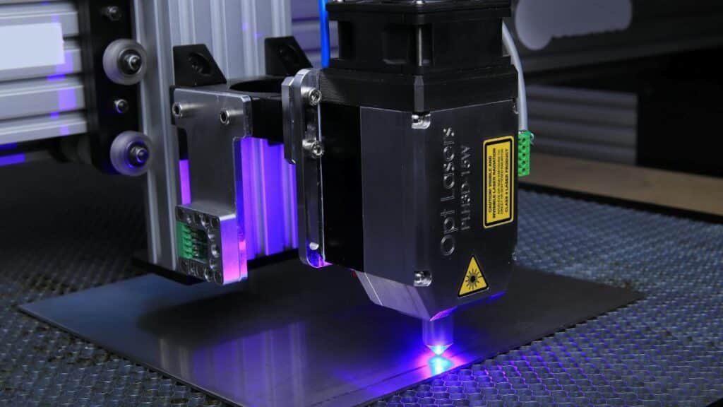 Close-up of a laser engraving machine operating on a metal surface with blue laser light.