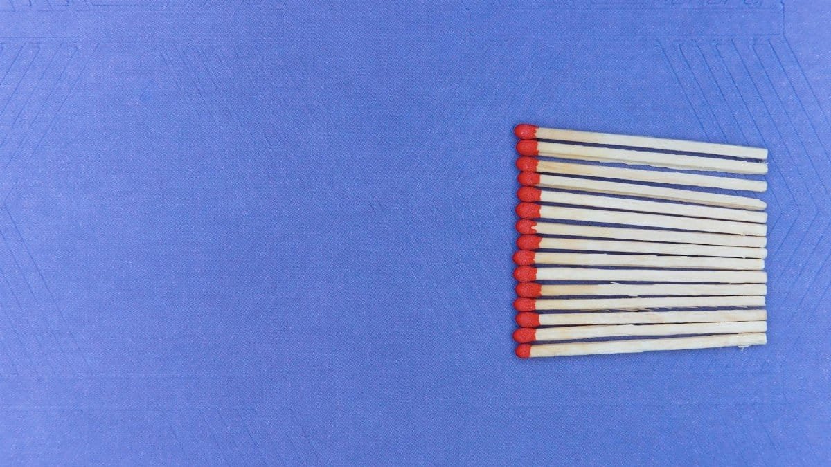 A neat arrangement of matchsticks on a textured purple background providing ample copy space.