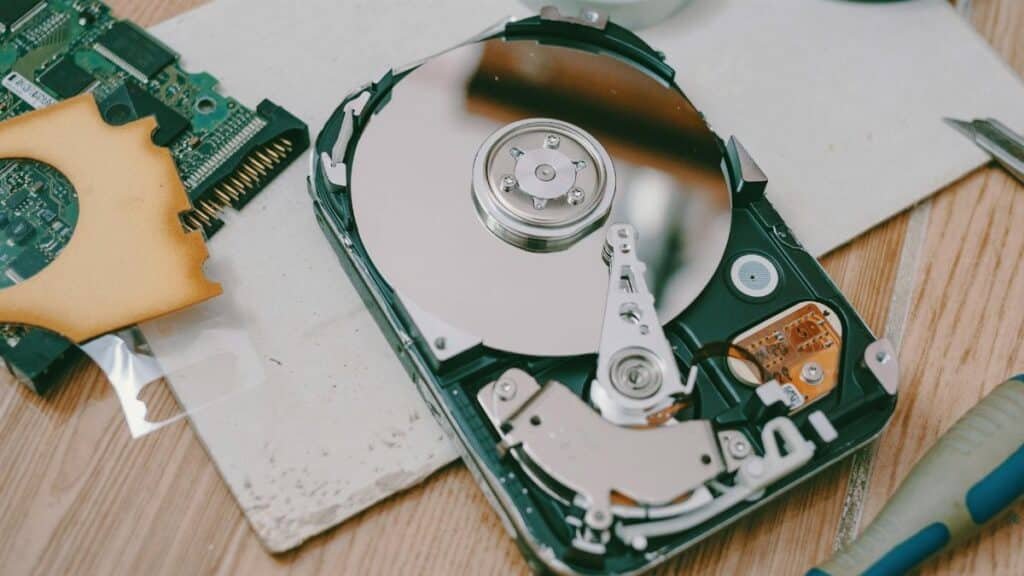 Close-up of a disassembled hard drive showing internal components on a wooden table.