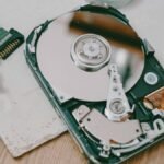 Close-up of a disassembled hard drive showing internal components on a wooden table.