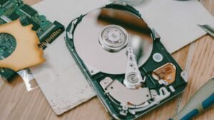 Close-up of a disassembled hard drive showing internal components on a wooden table.