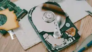 Close-up of a disassembled hard drive showing internal components on a wooden table.