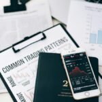 Overhead view of financial graphs and smartphone displaying stock market trends on a desk.