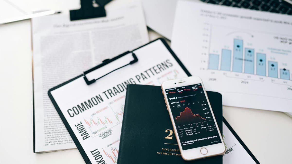Overhead view of financial graphs and smartphone displaying stock market trends on a desk.