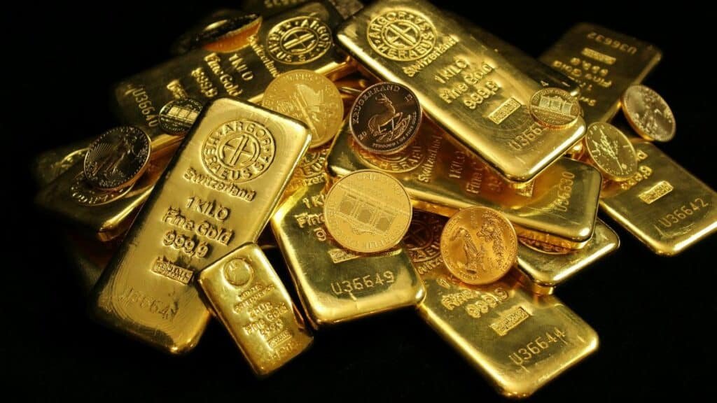 A close-up of gold bars and coins symbolizing wealth and investment on a black background.