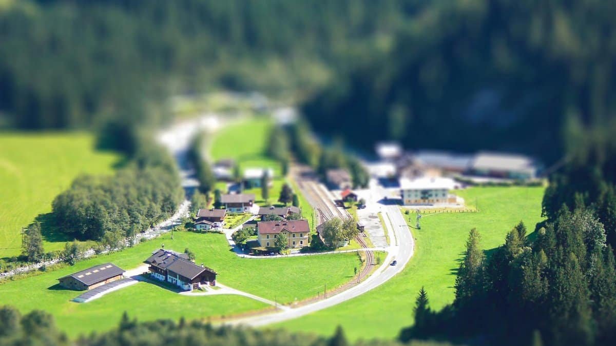 Aerial view of a charming rural village with tilt-shift effect, emphasizing its miniature appearance.